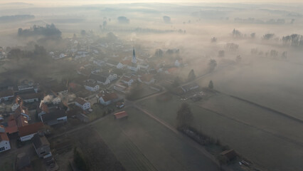Foggy Bavarian landscape during morning sunrise phase with forest background and small village close which is called P&ouml;rnbach and is located at the region of Pfaffenhofen