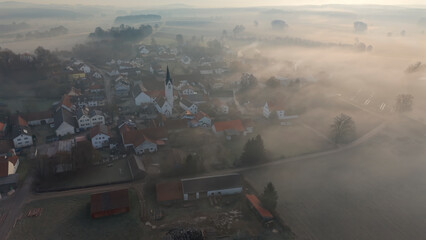Foggy Bavarian landscape during morning sunrise phase with forest background and small village close which is called P&ouml;rnbach and is located at the region of Pfaffenhofen