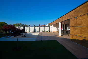 Modern villa with a private swimming pool and expansive wooden deck, featuring an outdoor dining area under a tiled roof. Enjoy luxurious living and relaxation in a beautiful, sunlit setting.