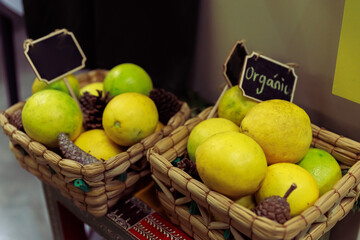 Two Woven Baskets Filled with Organic Yellow and Green Lemons and Pine Cones Displayed with Chalkboard Sign