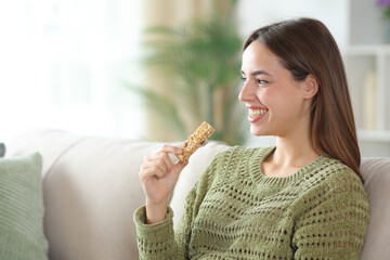 Happy woman in green holding granola looking away