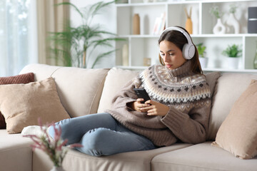 Serious woman in winter watching media online at home