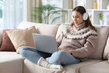 Serious woman in winter wearing headphone watching media