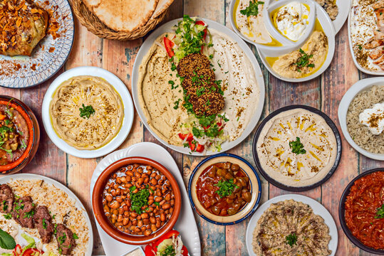 A plate of Lebanese-style baba ghanoush, accompanied by other mezze such as hummus, tabbouleh, and stuffed grape leaves, on a wooden table.
