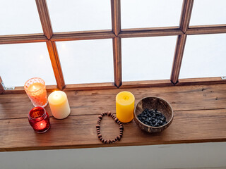 Candles and rosary near old window in monastery