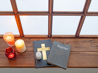 Holy bible, psalter and rosary beside old window in monastery