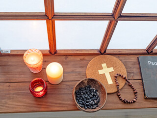 psalter, candles and rosary beside old window in monastery
