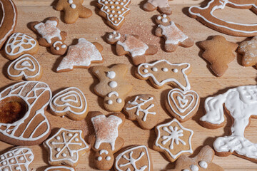 Assorted iced gingerbread cookies shaped like hearts, stars, trees and little people spread out on a wooden board.
