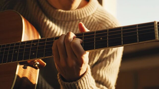 Man plays brown acoustic guitar with fingers, practicing chords for music song or hobby. Musical string instrument.