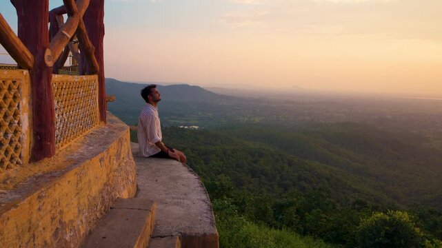 Hikers trekking during sunset in the mountains under a partly cloudy sky, with a temple creating a breathtaking backdrop at Samai Mata Mandir, Banswara, near Udaipur, Rajasthan, India.