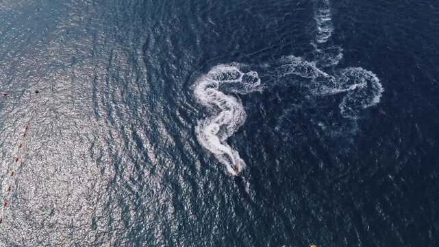 Aerial view of a watercraft leaving a trail of white water against the textured dark blue ocean surface, Ksamil, Vlore County, Albania.