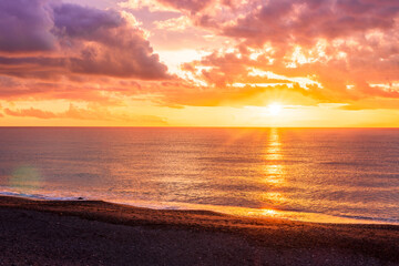 Dramatic seascape of sunset or sunrise sky with clouds during morning or evening. Dramatic sunset over the sea with orange clouds and sun above ocean water