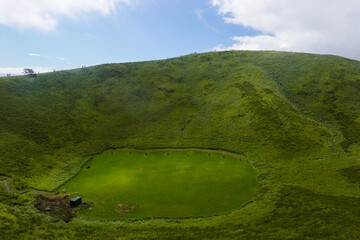 Green crater like hollow in bright grassy hillside plateau © SILI