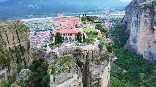 Aerial view of the Meteora Monastery perched atop towering rock formations, contrasting with the town nestled in the valley below, Kalabaka, Trikala, Greece.