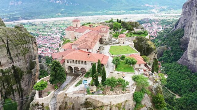 Aerial view of the incredible Meteora Monasteries perched atop towering rock formations, contrasting sharply with the town below, Kalabaka, Trikala, Greece.