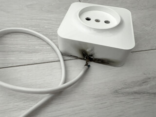 Damaged extension cord with burnt marks and frayed wires, showcasing potential hazards of electrical malfunctions and the importance of safety measures in home environments