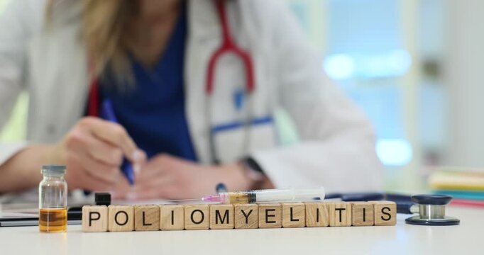 Wooden cubes spell word Poliomyelitis on doctor desk highlighting vaccination theme. Female medic in coat writes notes on disease at table in clinic