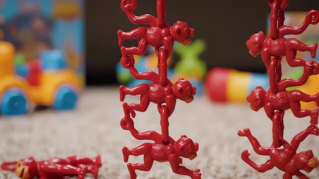 Hand Assembles Red Monkey Chain Toy on Carpet Close Up Shot
