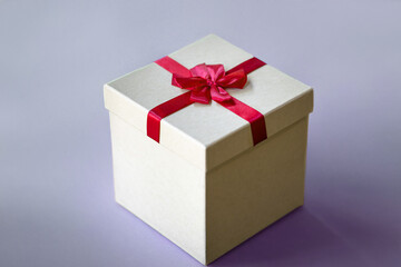 Single Beige Gift Box with Red Bow on Subtle Lavender Background, Minimalist Celebration Concept
