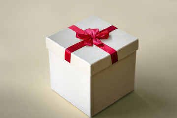 Simple Beige Gift Box with Red Ribbon on Warm Cream Background, Neutral Holiday Gifting