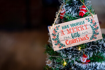 Festive Wooden Sign "Merry Little Christmas" Hanging on Decorated Tree with Copy Space, Holiday Background