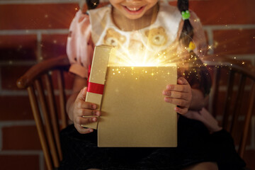 Little Girl Opening a Big Magical Christmas Gift Box with Dazzling Light Burst and Sparkles, Joyful Holiday Moment