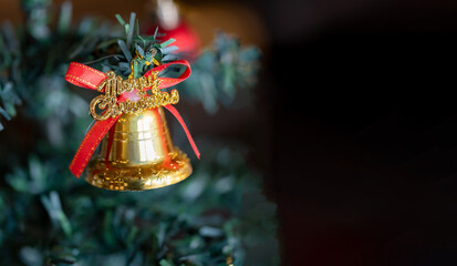 Golden Christmas Bell Ornament with Red Ribbon Hanging on a Festive Green Christmas Tree Branch