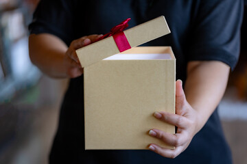 Hands Opening a Simple Empty Cardboard Gift Box with Red Ribbon, Ready to be Filled for Christmas or Holiday Gifting