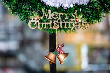 Festive Merry Christmas Sign and Golden Bells on Green Garland Decoration for Holiday Season Background.