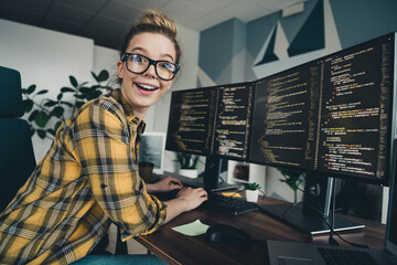 Qualified programmer enthusiastically developing code on dual monitors in stylish workspace with casual and vibrant energy