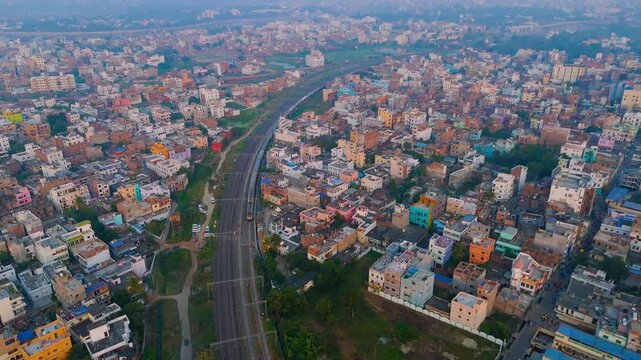 Aerial View of Indian Passenger Train Passing Through Dense Urban Residential Neighborhood at Sunset