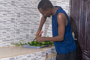 cute man in her home kitchen, focused on the task of cutting fresh, green vegetable