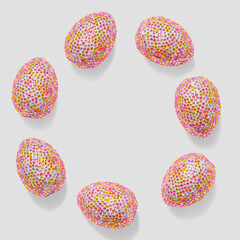 Sparkling easter eggs as round shape layout. Minimal festive frame with copy space, abstract aesthetic food. Pink eggs with bright texture of rhinestones or sequins, easter spring holiday background.
