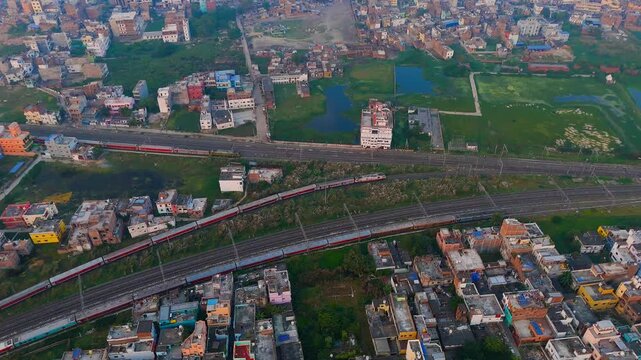 Aerial View of Indian Passenger Train Passing Through Dense Urban Residential Neighborhood at Sunset