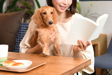 自宅で犬と読書するアジア人の若い女性
