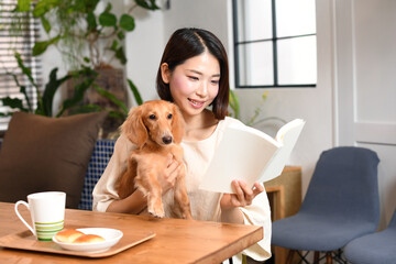 自宅で犬と読書するアジア人の若い女性