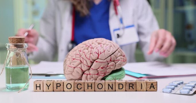 Psychiatrist reviews medical history of patient paying close attention to long-standing symptoms. Wooden blocks form word Hypochondria on table