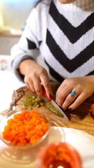 Close examination of hands slicing carrots and herbs carefully