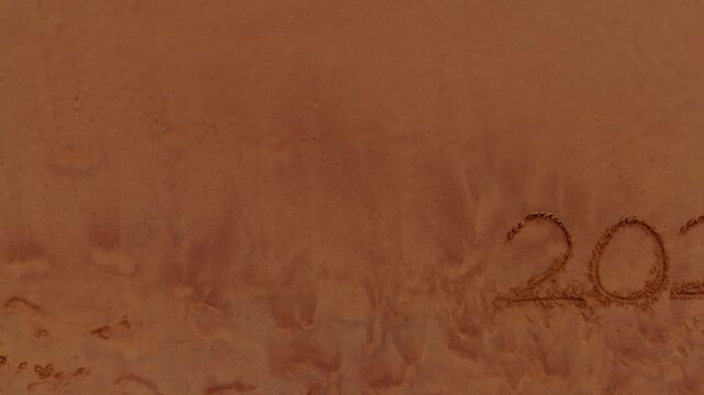 Drone Shot track right Revealing 2026 Written in Beach Sand at Evening 