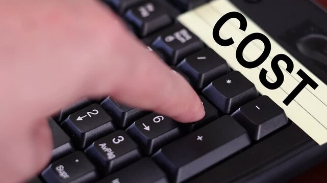 Un primer plano de un teclado con n&uacute;meros con el dedo de una mujer adulta marcando los n&uacute;meros y una nota amarilla con la palabra costo