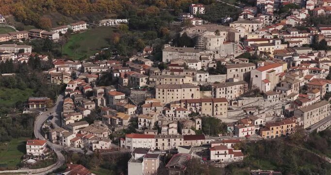 Aerial view of the structures with their warm tones and red roofs, nestled amongst the green trees, creating a picturesque scene, Gesualdo, Irpinia, Italy.