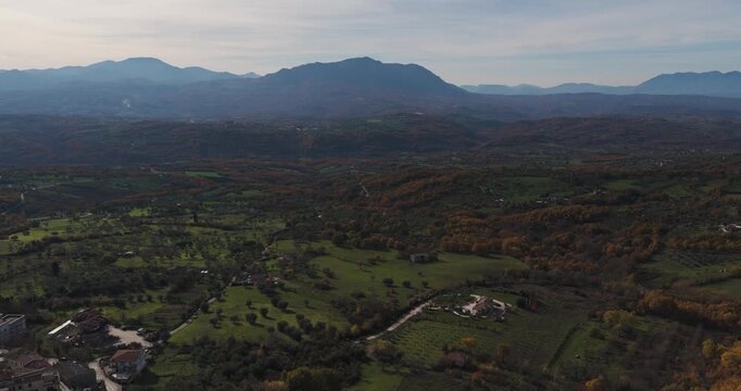 Aerial view of the vast landscape shows a mix of green fields and dense forests under the clear sky, Gesualdo, Irpinia, Italy.