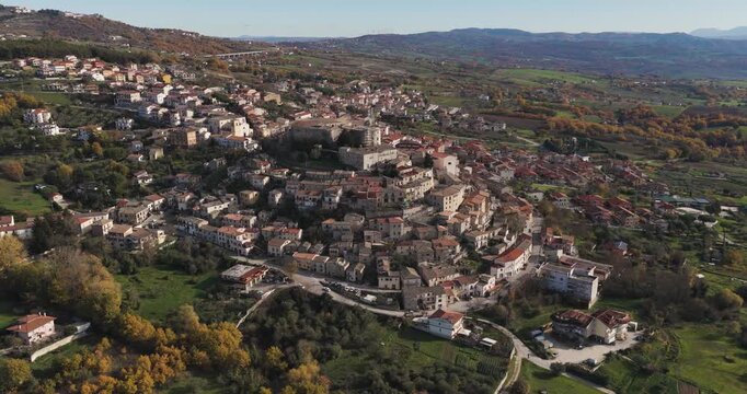 Aerial view of the town of Gesualdo, a symphony of terracotta roofs and stone buildings nestled amidst rolling hills and verdant trees, Gesualdo, Irpinia, Italy.