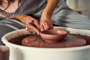 Potter Shaping Wet Chocolate color Clay on a Spinning Wheel, Focused Hands Creating Ceramic Vessel                              