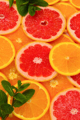 Slices of oranges and a grapefruits and mint as a background.