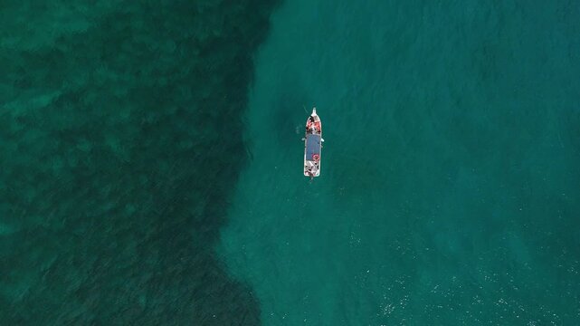 Aerial view of a boat sailing on the crystal clear turquoise waters of the Caribbean Sea, Mahahual, Quintana Roo, Mexico.