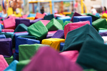 Close-up view of a pile of multi-colored, soft, cloth-covered blocks in a play area.