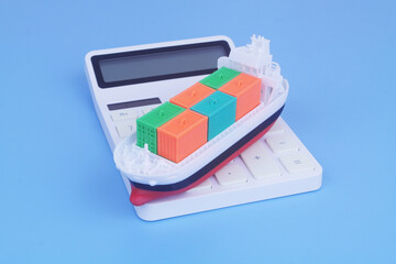 Cargo ship with containers on calculator on blue background. Sea ​​transportation budget and price concept.