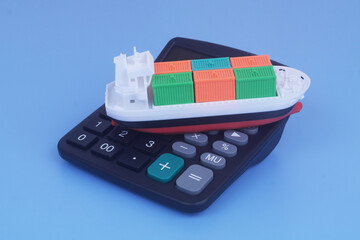 Cargo ship with containers on calculator on blue background. Sea ​​transportation budget and price concept.