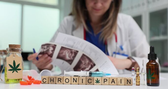 Wooden cubes spell words Chronic Pain near cannabis medicine bottles. Woman doctor studies ultrasound images managing long term symptom relief